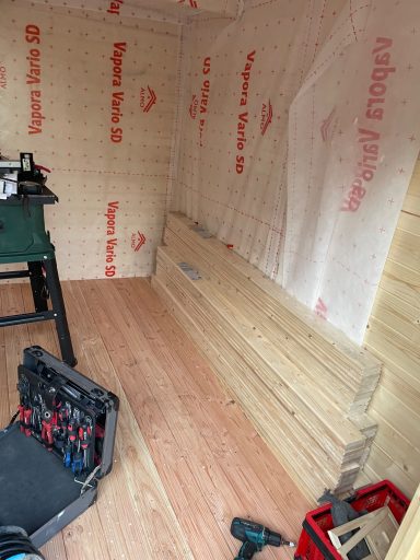 Inneraum eines Holzgebäudes mit isolierten Wänden und Werkzeugen auf dem Boden.